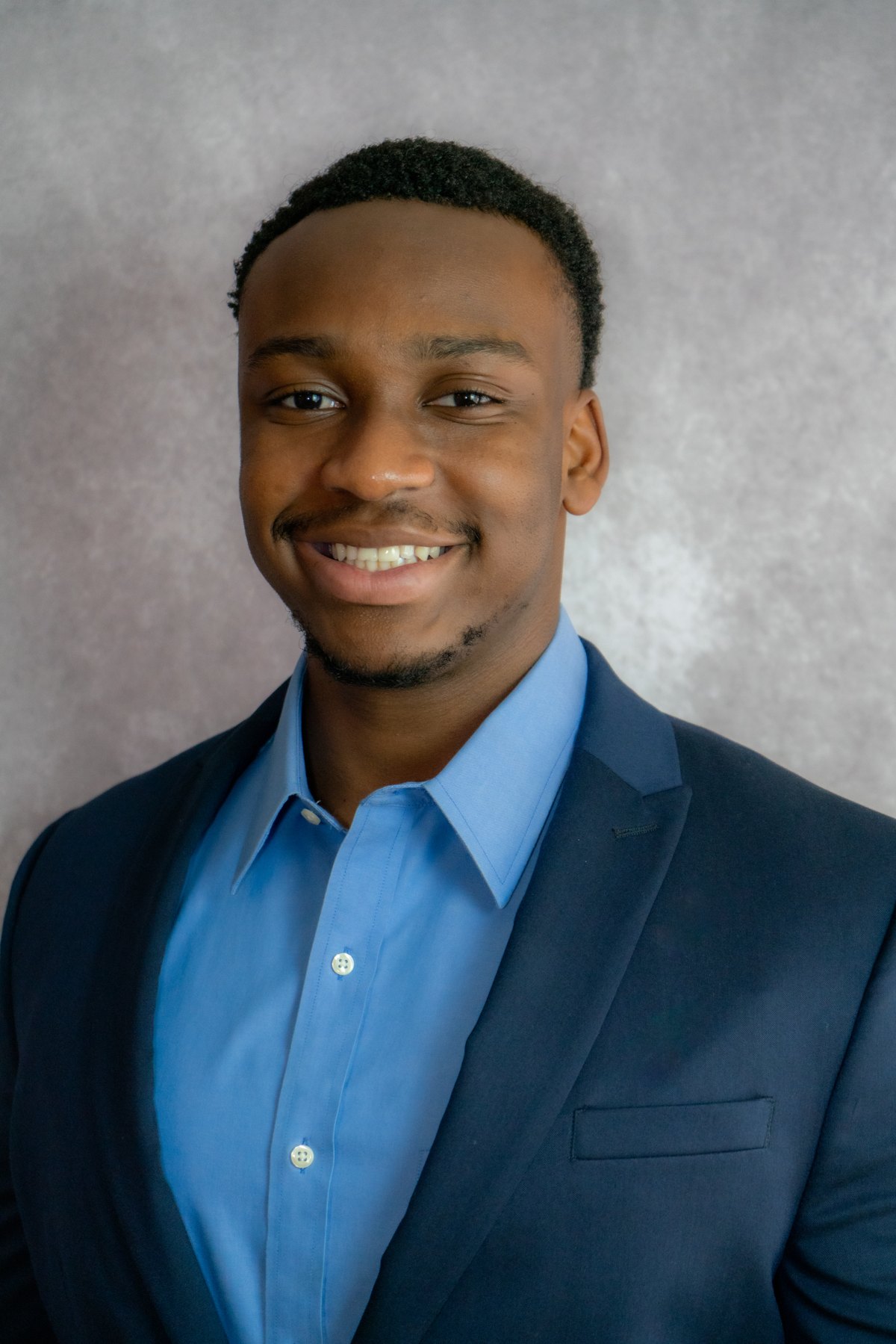 Professional headshot with glasses, soft grey backdrop